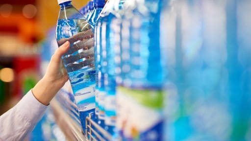 A person removes a water bottle from a store shelf.